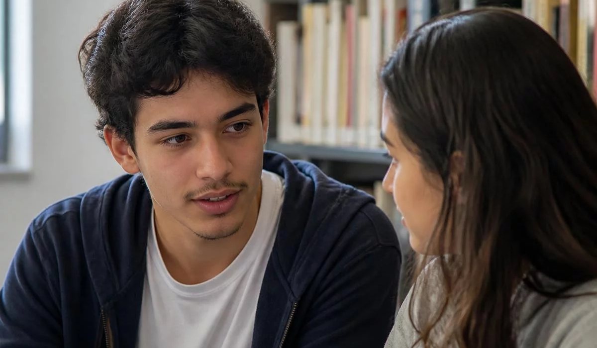 Pessoas conversando de pé junto às estantes antes de o encontro abrir